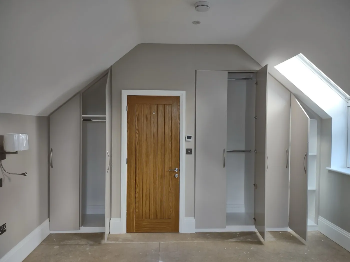 Fitted loft wardrobes with doors open showing hanging rails and shelving